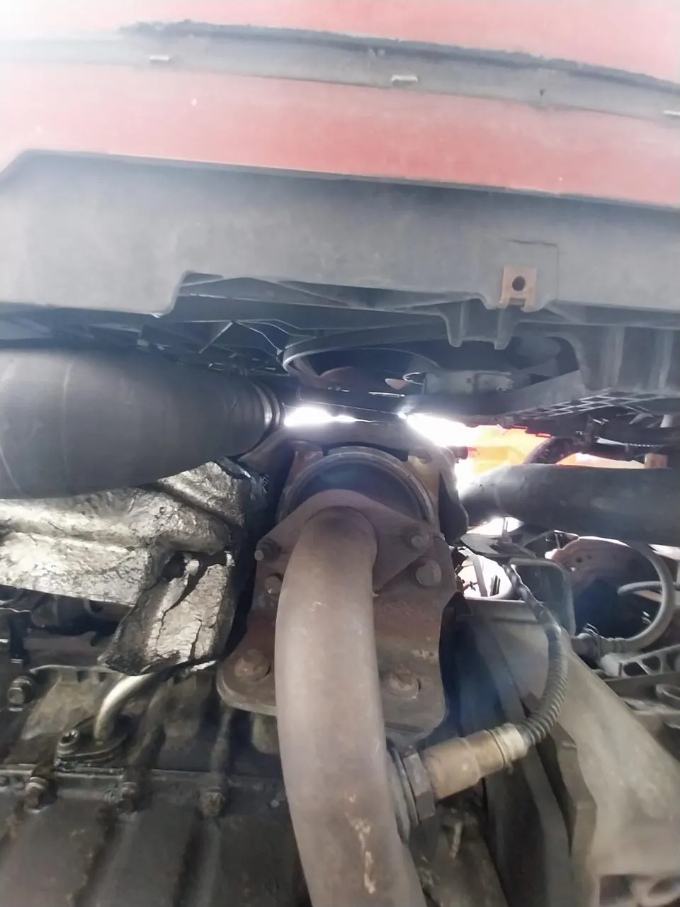 Parte baja del motor de un coche usado con restos de aceite y suciedad pegada por rezumes